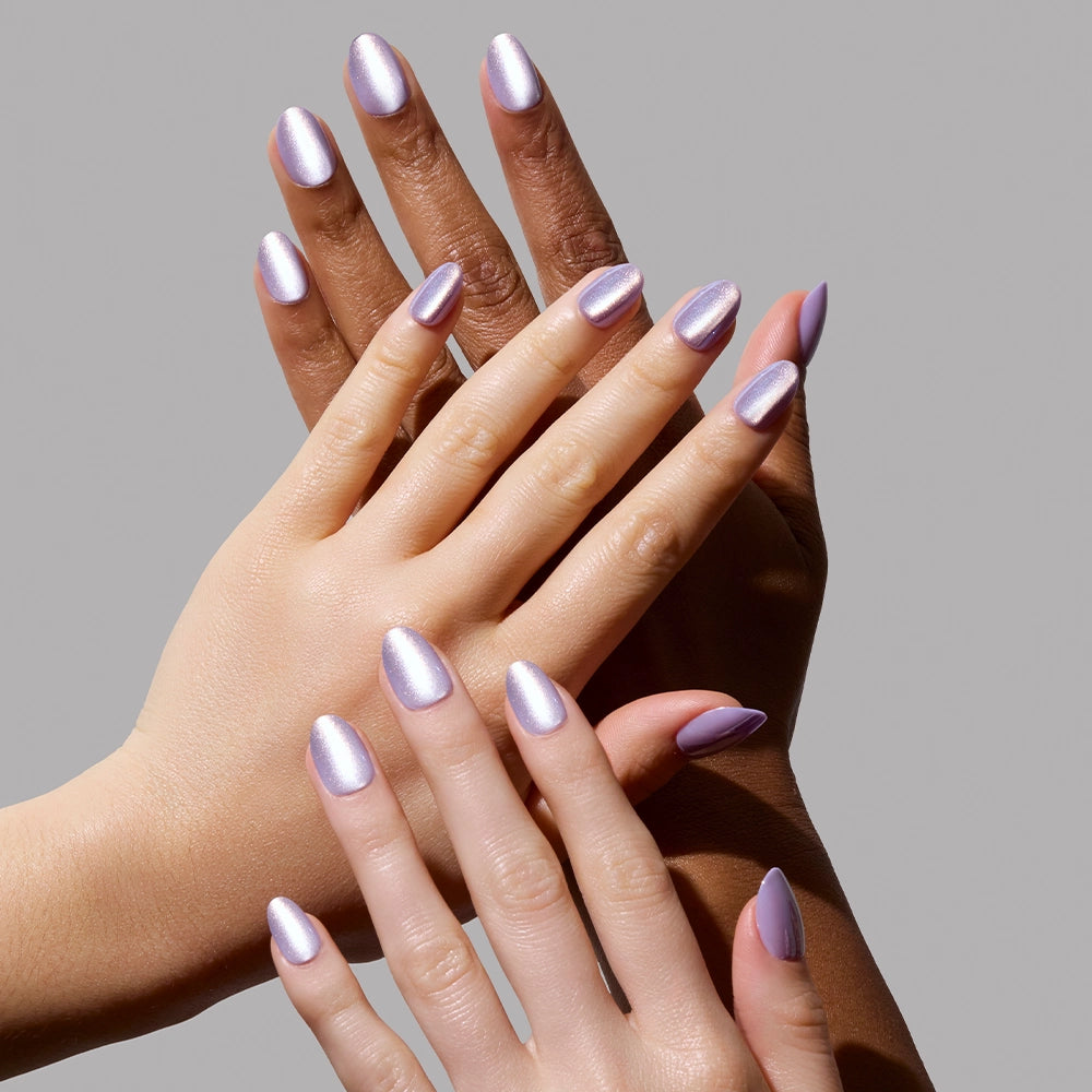 Three hands with varied skin tones display manicured nails painted in glamnetic’s Mermaids Tail, an iridescent purple polish, against a plain gray background. Their elegant overlap perfectly showcases the dazzling nail color. - Product image