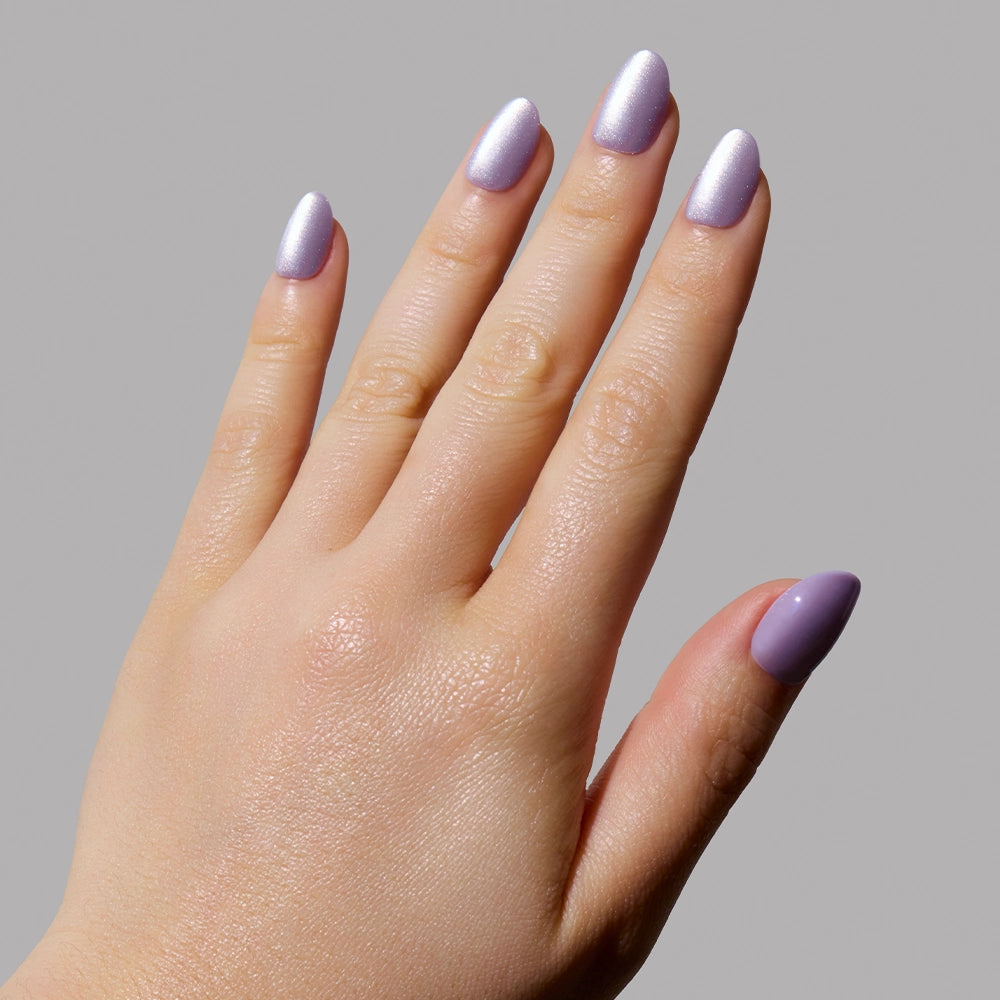 A hand with manicured nails painted in glamnetic’s Mermaids Tail iridescent purple is shown against a plain gray background. - Product image