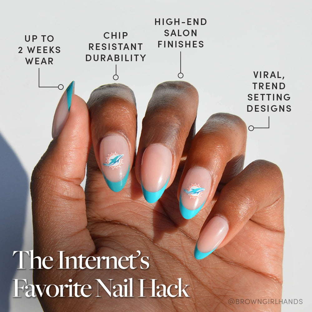 A hand with medium brown skin displays almond-shaped nails featuring turquoise French tips and a white accent, created with the glamnetic Miami Dolphins Press-On Nail Set. Enjoy trendy nail art with long wear, chip resistance, and salon quality. - Product image