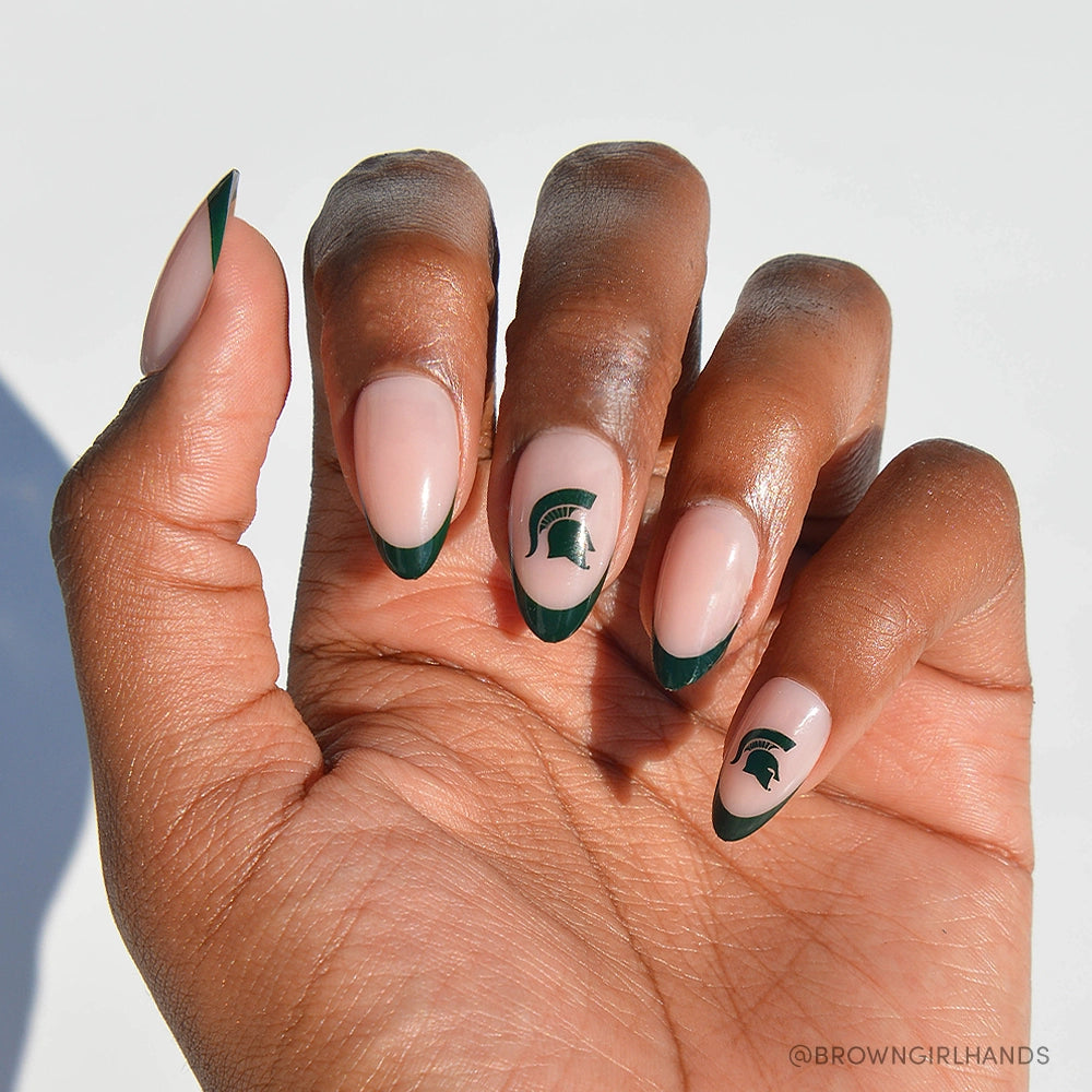The glamnetic Michigan State Spartans Press-On Nail Set features almond-shaped press-ons with a nude base, green French tips, and Spartan Strong helmet logos—a perfect choice for fans looking for stylish MSU-inspired nails.