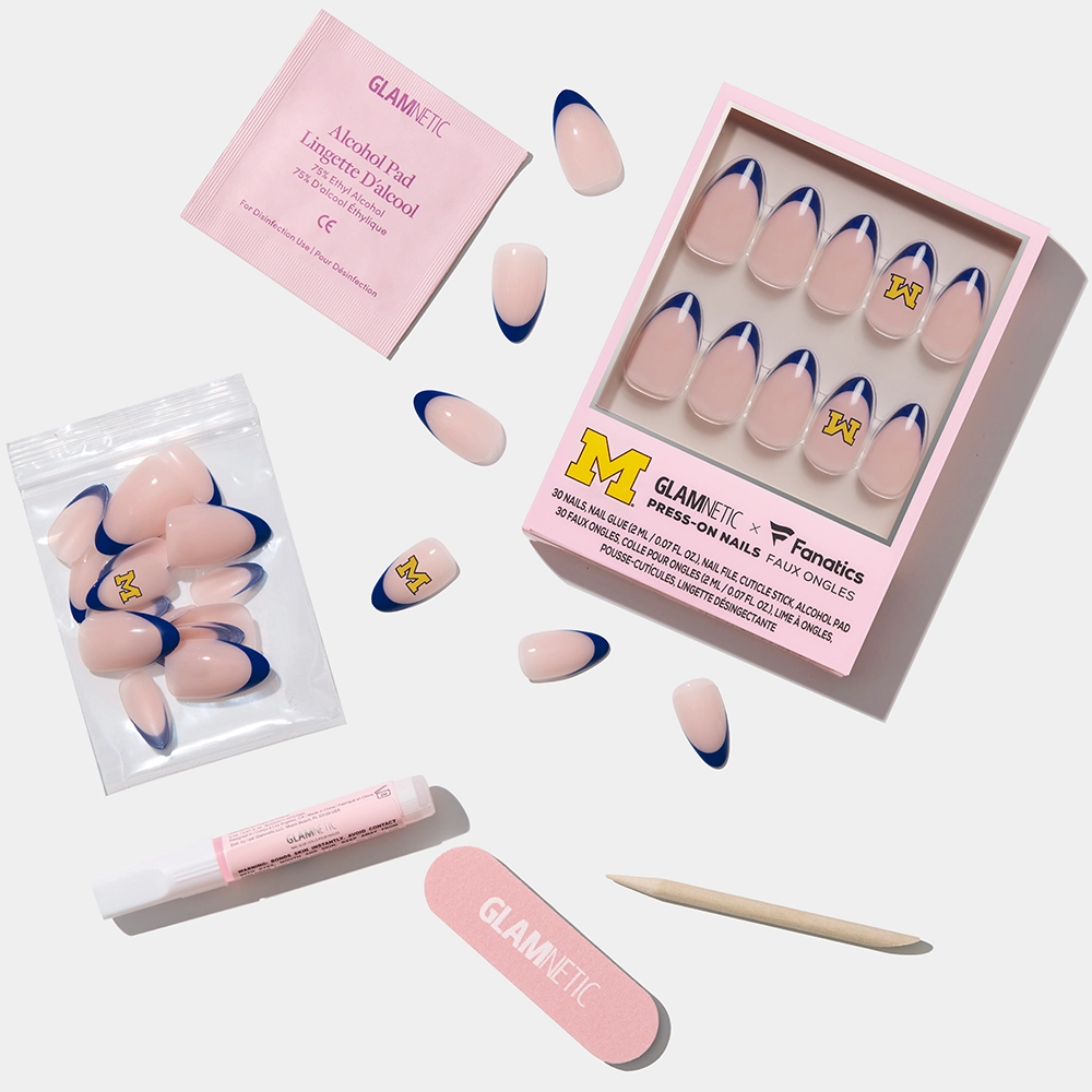 The glamnetic Michigan Wolverines Press-On Nail Set features pink base nails with blue French tips and a yellow M logo, plus a pink nail file, wooden cuticle stick, glue, alcohol pad, and extra nails for game-day style. - Product image