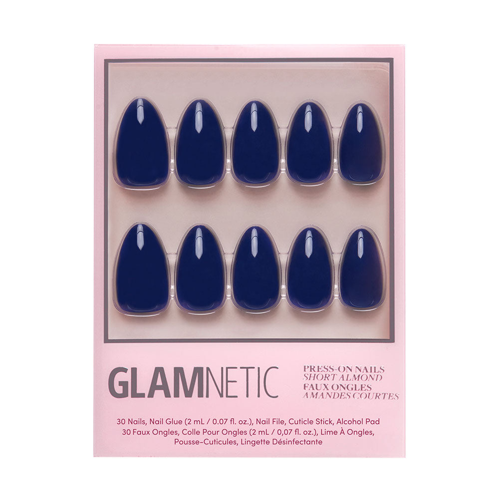 The glamnetic Midnight Blue press-on nails feature a short almond shape and glossy dark blue finish, arranged in two rows on a pink card inside clear packaging. - Product image