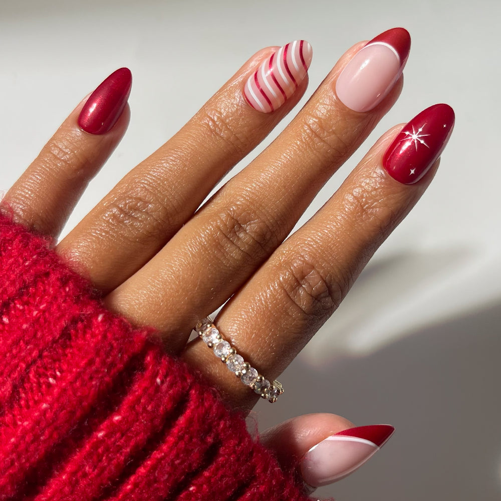 Glamnetic Mint to Be short almond press-on nails featuring a mix of red polish, white-and-red candy cane stripes, red French tips, and a starburst design.