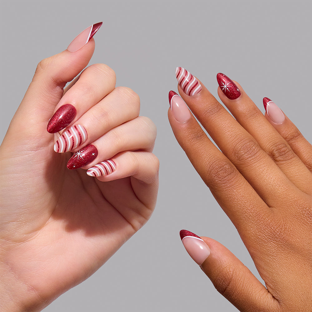 Glamnetic Mint to Be press-on nails on two hands, featuring short almond shapes with red-and-white candy cane stripes, solid red glitter, and red French tips with small white star accents. - Product image