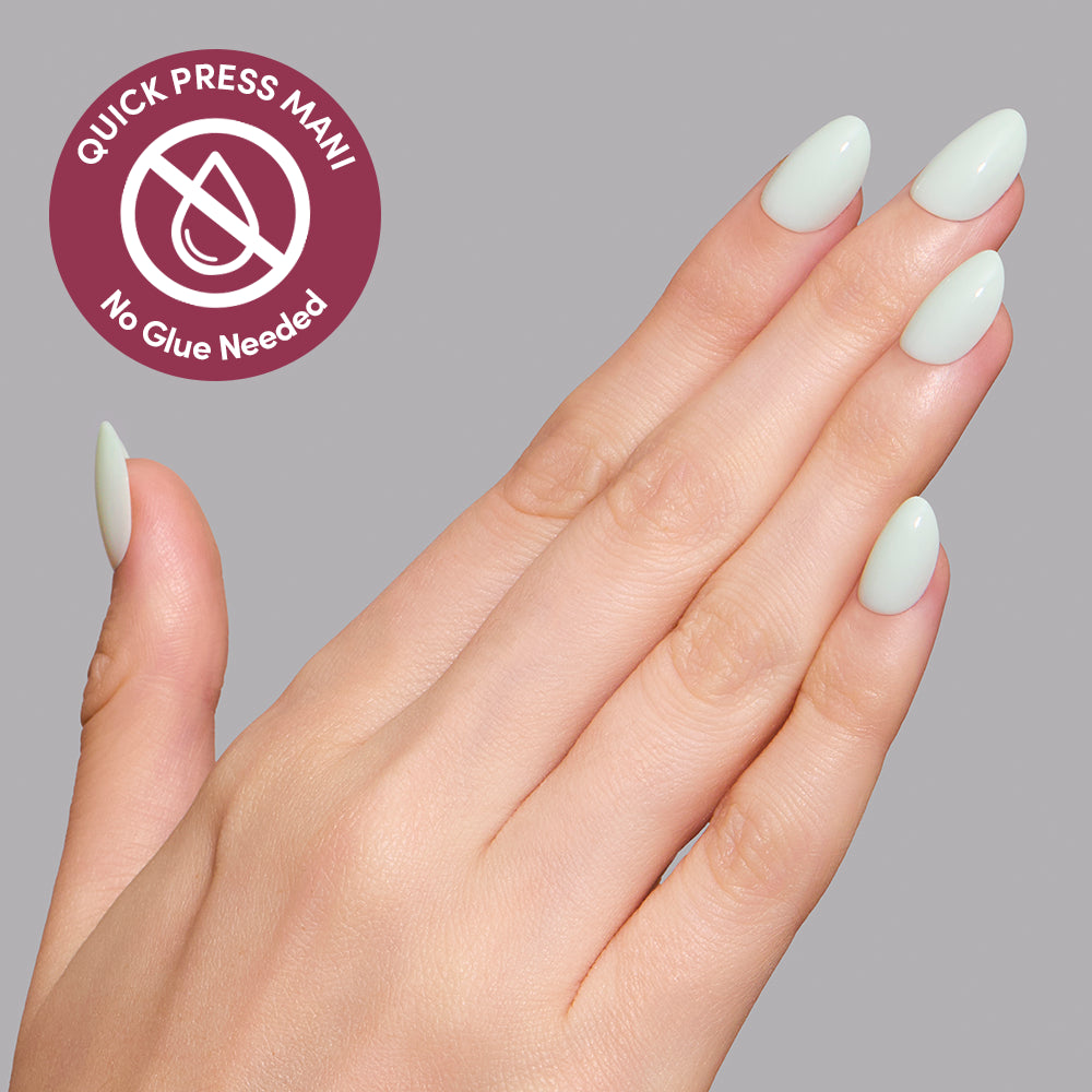 A hand wearing extra short oval, pale mint green Minty Cloud press-on nails next to a circular badge that reads Quick Press Mani, No Glue Needed. - Product image