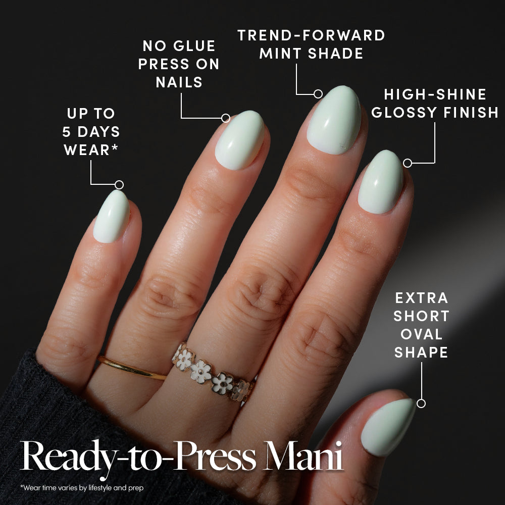 Hand wearing extra short oval Minty Cloud press-on nails in mint green with text overlays highlighting the glossy finish, five-day wear, and application method. - Product image