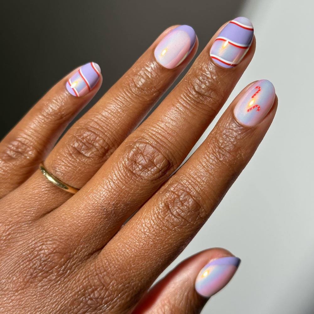 Short, rounded Glamnetic Miss Minty press-on nails featuring a pearlescent lavender base decorated with red and purple candy cane-inspired stripes for a festive holiday mani.