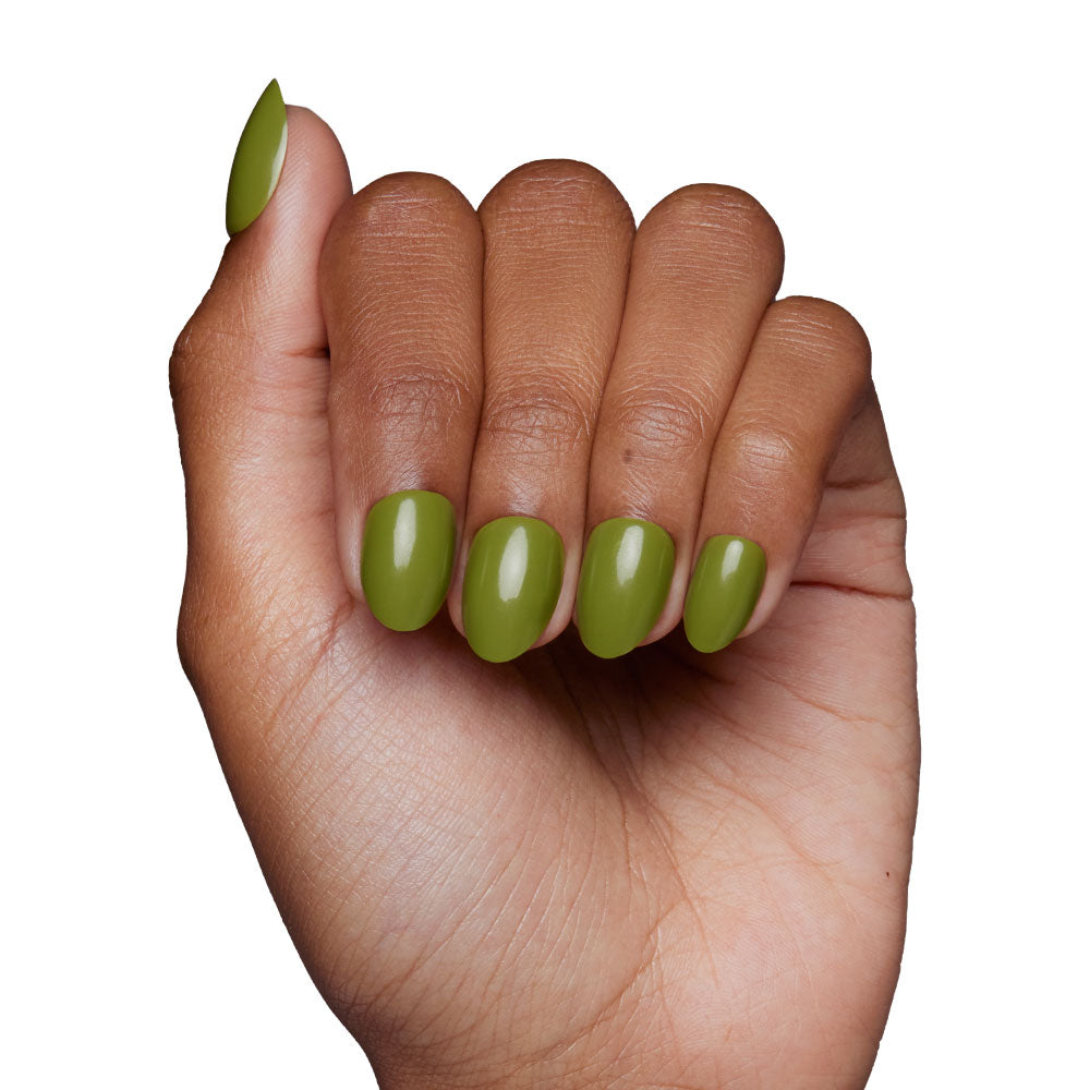 A hand with medium brown skin forms a fist, showing nails painted in glamnetic’s Moss Green—a glossy olive shade perfect for fall—against a plain white background. - Product image