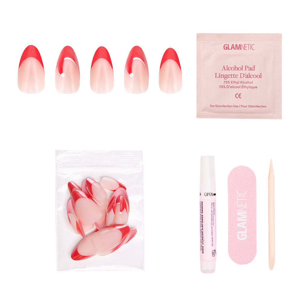 The glamnetic Mrs. Claus set includes red French tip press-on nails with Santa hat accents, extra nails in a small bag, an alcohol pad, nail file, cuticle stick, and glue—all displayed on a white background. - Product image
