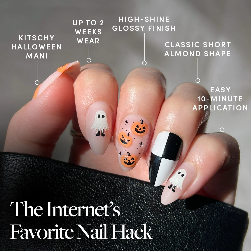 Hand with My Boo Halloween-themed short almond nails from glamnetic, featuring press-on designs of ghosts, jack-o-lanterns, and black and white accents. Text highlights a 10-minute application, glossy finish, classic shape, up to 2 weeks wear, and a kitschy Halloween look. - Product image