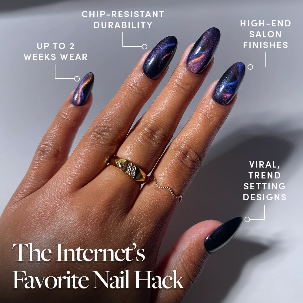 A hand adorned with glossy, dark, multicolored iridescent Mystic Topaz press-on nails by glamnetic, accessorized with two rings. Text highlights chip-resistant quality, a high-end finish that lasts up to 2 weeks, and on-trend designs. Title: The Internet’s Favorite Nail Hack—get salon-quality mystic topaz nails from glamnetic effortlessly at home. - Product image