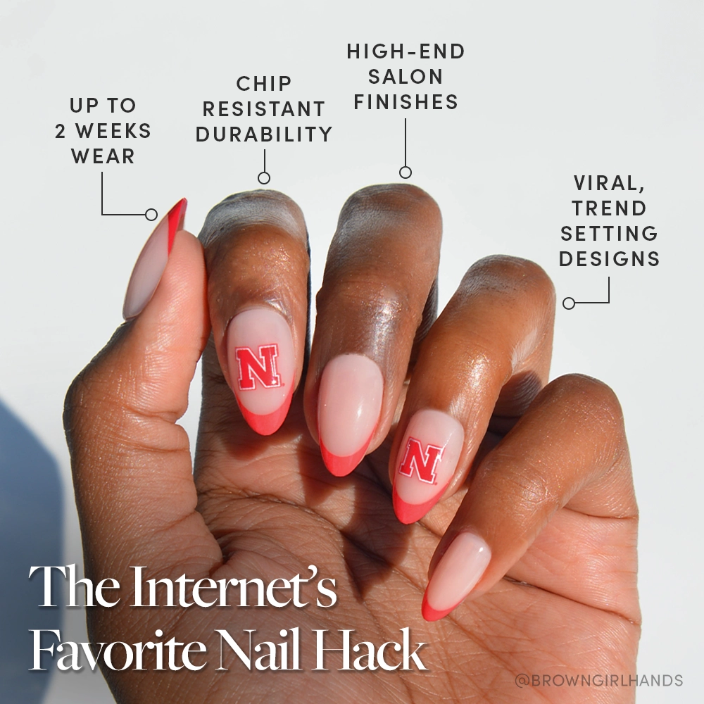 A hand with almond-shaped nails shows pink polish, bold red French tips, and red N designs—just like the glamnetic Nebraska Cornhuskers Press-On Nail Set: trendy, durable press-ons for salon-quality, long-lasting wear. - Product image