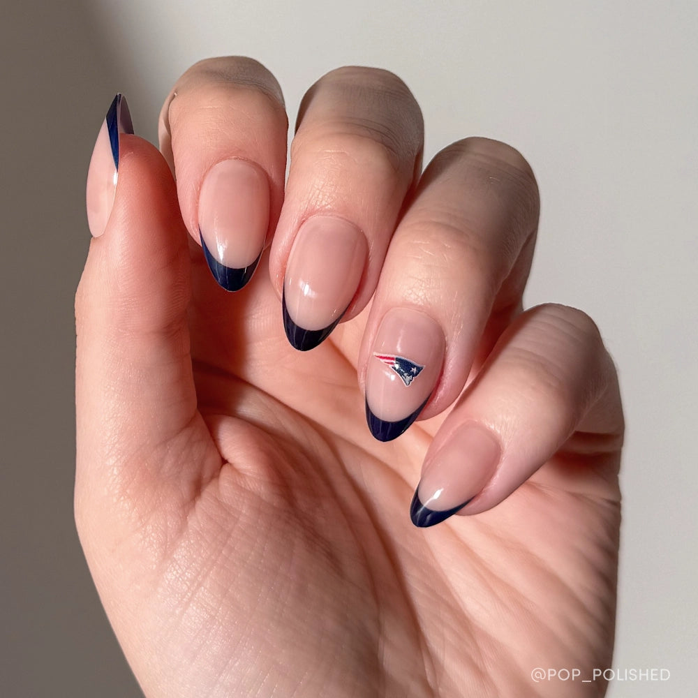 The New England Patriots Press-On Nail Set by glamnetic features almond-shaped nails with navy blue French tips and a signature Patriots logo decal—perfect for devoted fans.