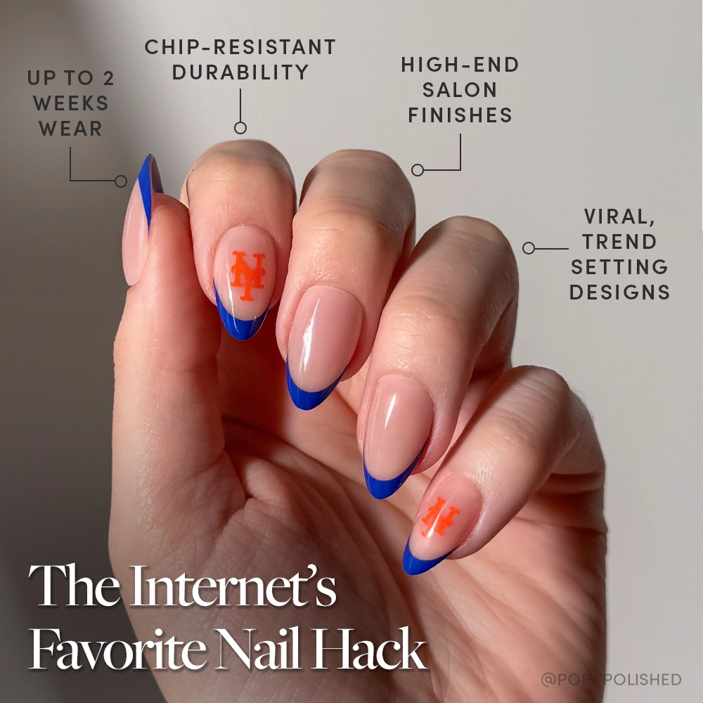 A hand with long, almond-shaped glamnetic nails features blue French tips and orange NY logos. The New York Mets Press-On Nail Set offers up to 2 weeks wear, chip-resistant durability, luxe finishes, and viral team-inspired designs. - Product image