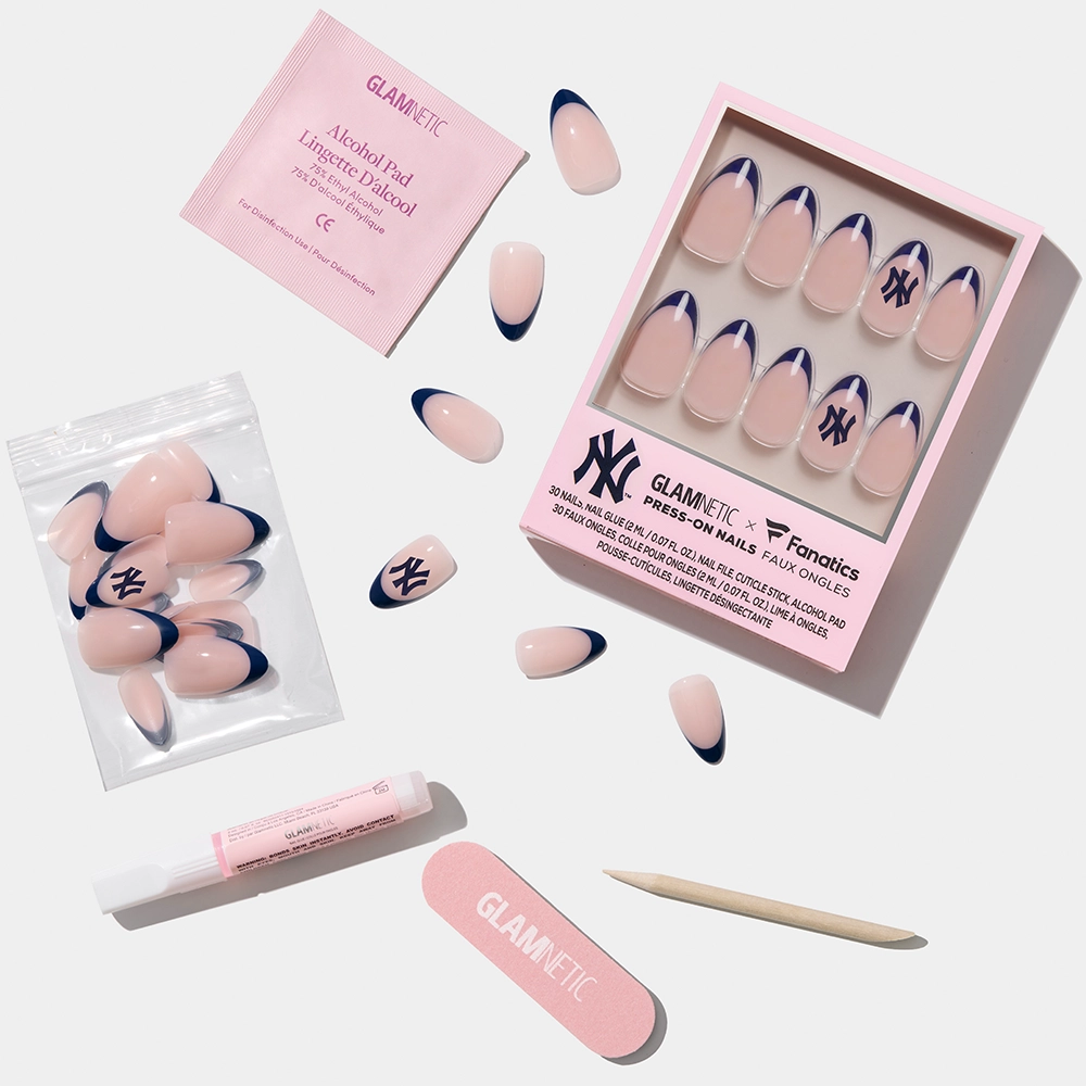 The glamnetic New York Yankees Press-On Nail Set features pink and navy French tips, some with the Yankees logo. Includes extra nails, nail file, wooden cuticle stick, nail glue, and alcohol pad—all on a white background. - Product image