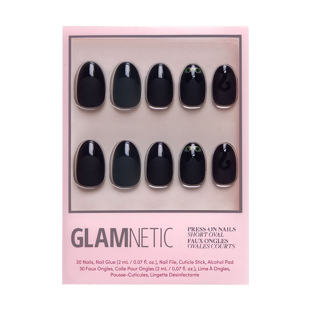 The Nine Lives nail set by glamnetic features black, velvet-finish cat eye nails with green accents on two tips, packed in pink Glamnetic packaging. The box includes 30 faux nails and nail glue. - Product image