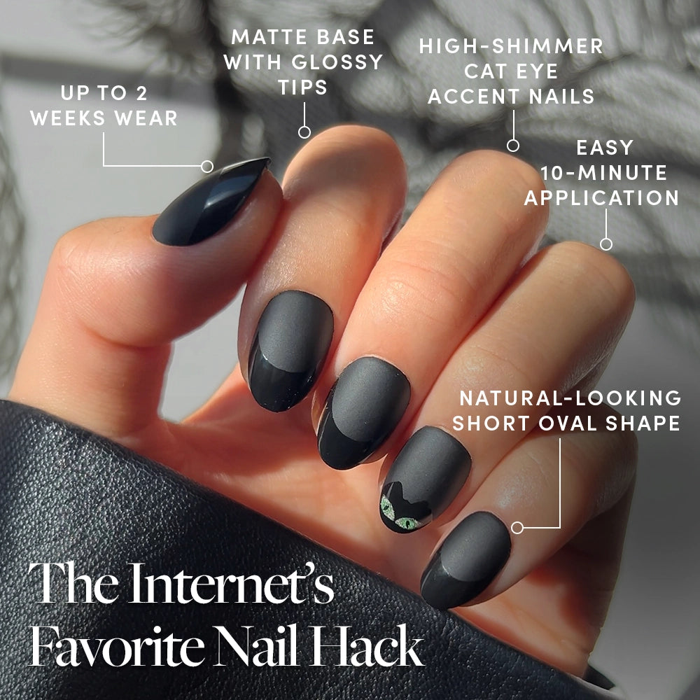 A hand showcases glamnetic’s Nine Lives premium press-on nails, featuring a matte black short oval shape, glossy tips, and a bold black cat-eye accent nail inspired by classic cat nails. The text highlights up to 2 weeks of wear, an easy 10-minute application process, and a natural-looking finish. - Product image