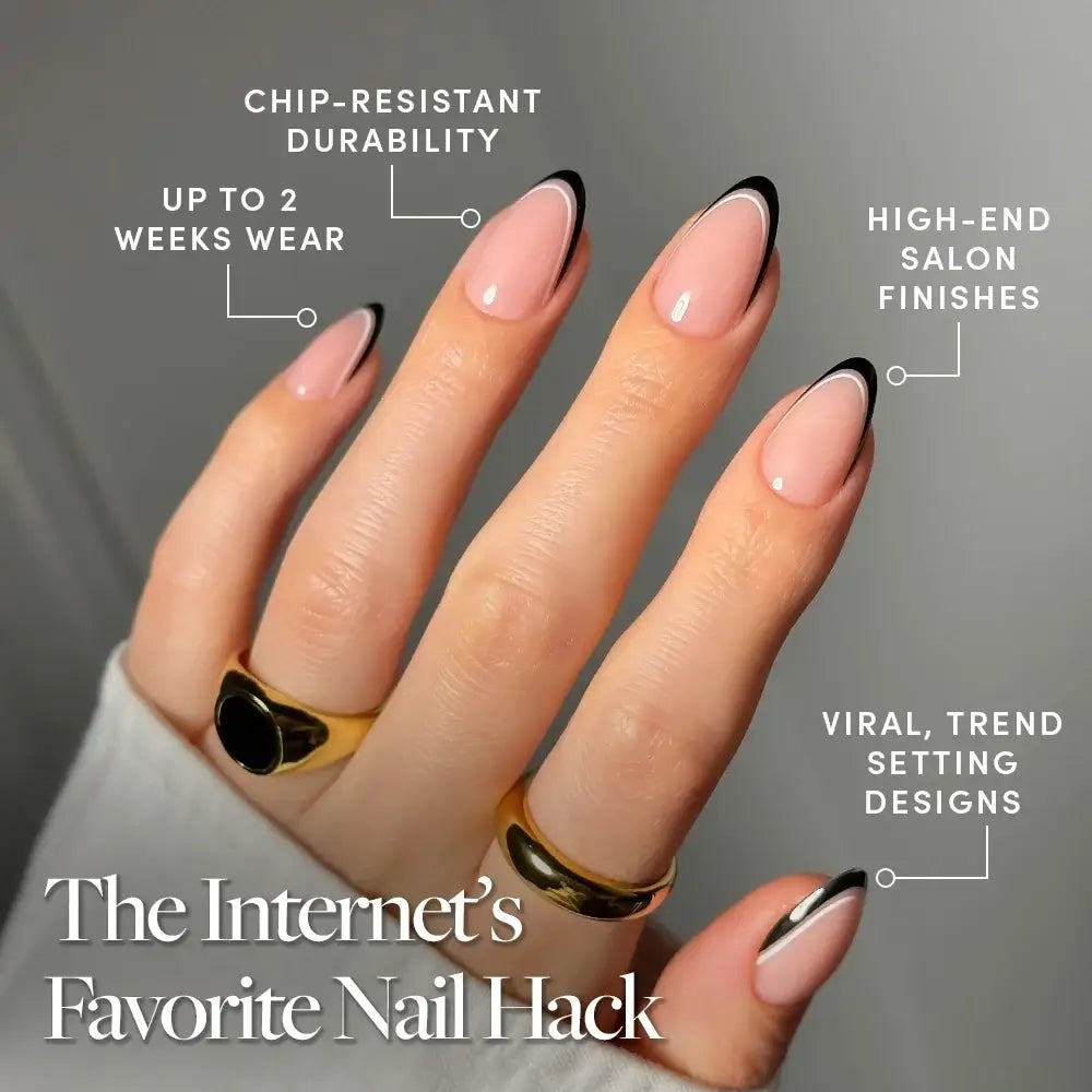 A hand showcases glamnetic’s NO IN BETWEEN nails—long, almond-shaped tips with a light pink base and black micro French tips. Text bubbles highlight their chip resistance, two-week wear, salon-quality finish, and trendy design. The hand is accessorized with two gold rings. - Product image