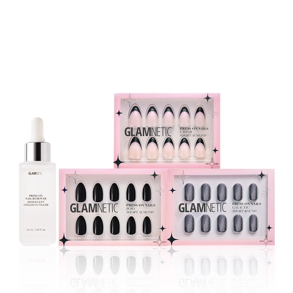 A dropper bottle labeled glamnetic sits next to three boxes of glamnetic Noir Classics press-on nails in pink, black, and silver shades with pink packaging, all displayed against a white background. - Product image