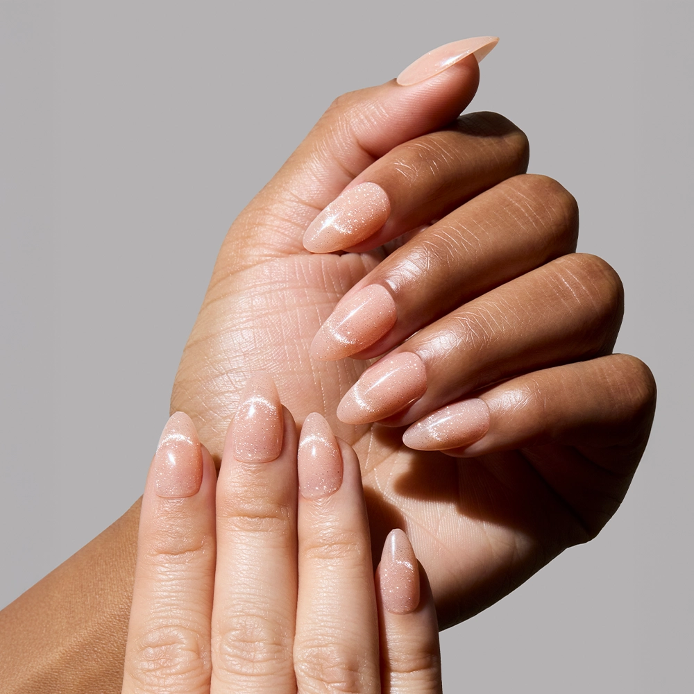 Close-up of hands wearing nude shimmer press-on nails from Glamnetic, showing subtle sparkle and natural finish. - Product image