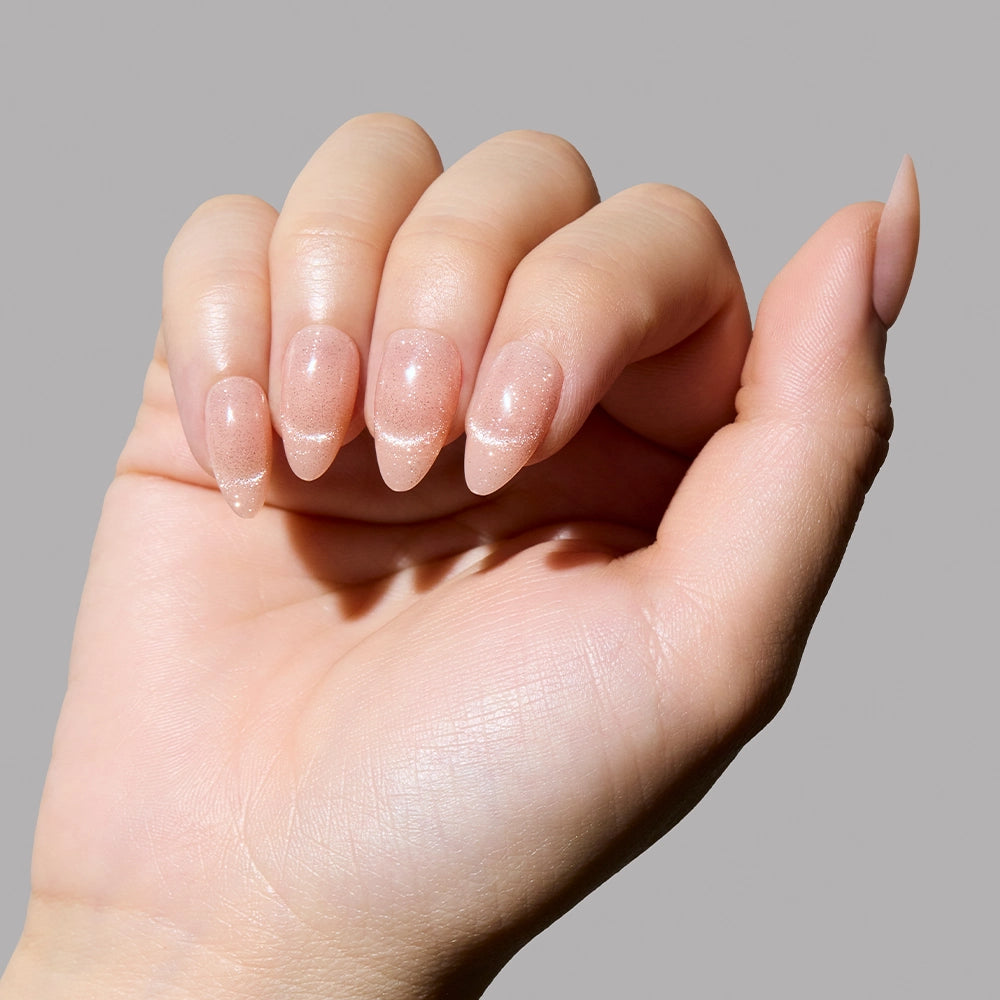 Natural hand pose displaying almond-shaped nude shimmer press-on nails with glossy finish. - Product image