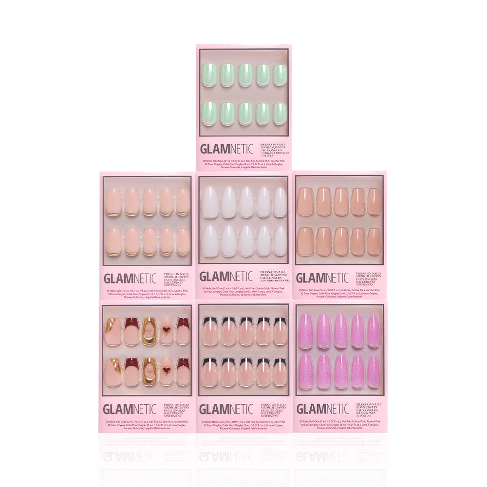 Seven boxes of glamnetic's Main Stage Moment salon-quality press-on nails in assorted colors and designs—green, white, pink, glittery purple with gold and heart accents—are arranged in a pyramid against a white background. - Product image