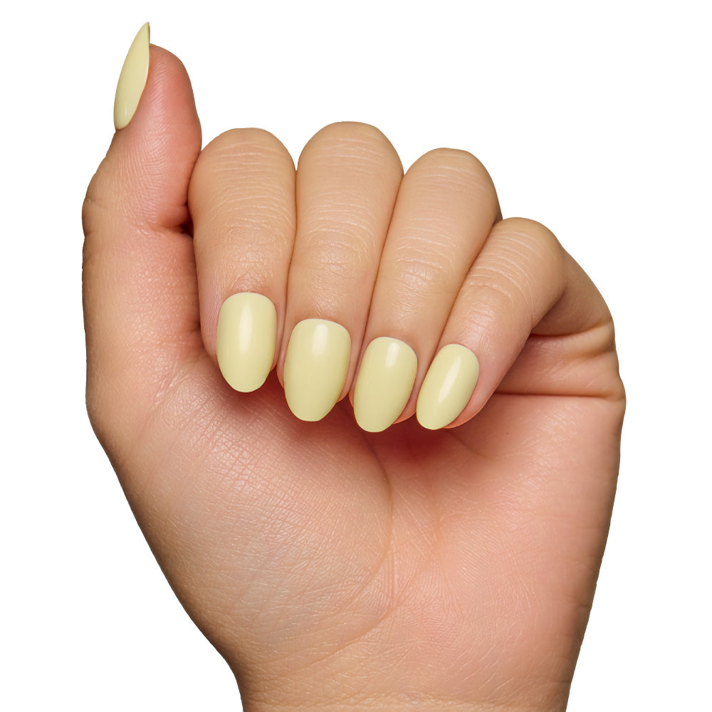 A hand with short oval nails, neatly manicured and painted in glamnetics Pastel Yellow nail set, is displayed against a white background for a salon-quality sheen. - Product image