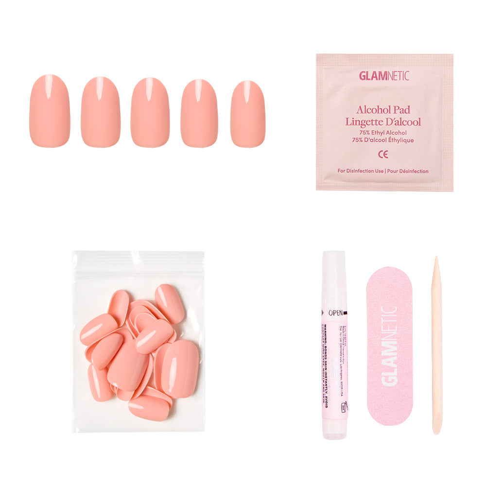 The Peach Coral Nail Set by glamnetic features reusable pastel peach nails, extra nails, nail glue, an alcohol pad, a pink file, and a wooden cuticle stick—all arranged on a white background. - Product image