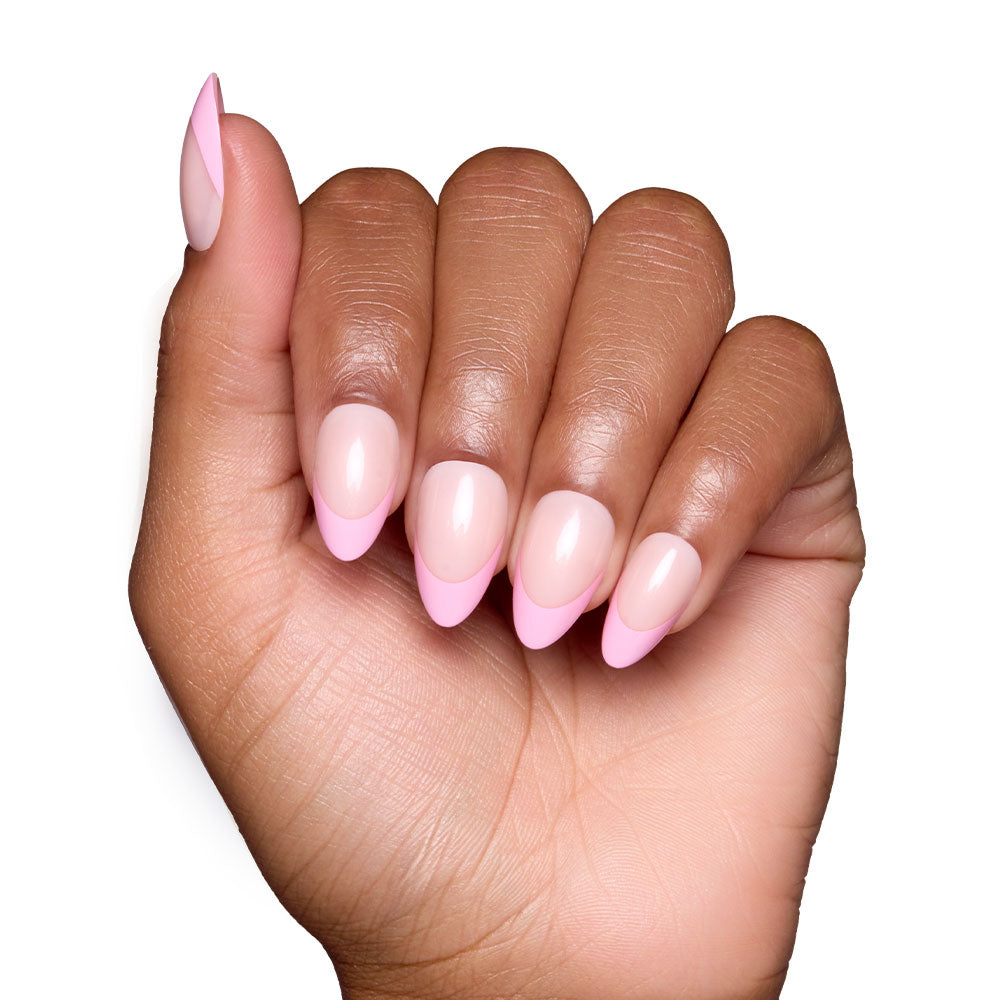 A hand with neatly manicured nails in Pink Macaron by glamnetic features a light pink almond base and bold French tips, perfectly displayed against a crisp white background. - Product image