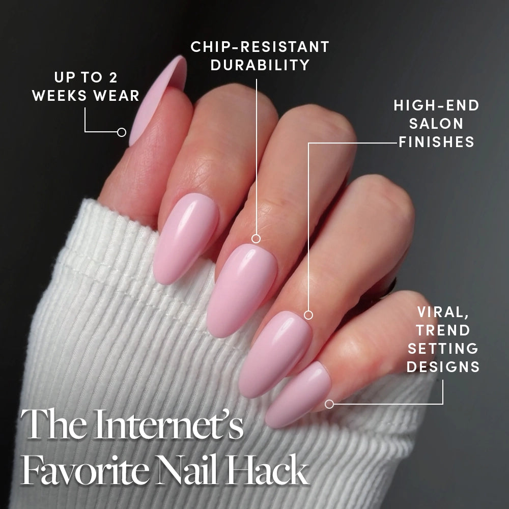 A hand with long, glossy glamnetic Pink Obsession press-on nails in light pink is shown against a dark background. Sweater sleeve partially covers the hand. Features: up to 2 weeks wear, chip-resistant, salon finish, and viral trendy design. - Product image