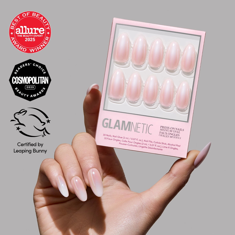 A hand with long, almond-shaped glamnetic Pink Pearl Press-On Nails featuring a soft ombre French tip holds a box of Pink Pearl nails. Beauty award logos from Allure, Cosmopolitan, and Leaping Bunny appear on the left. - Product image