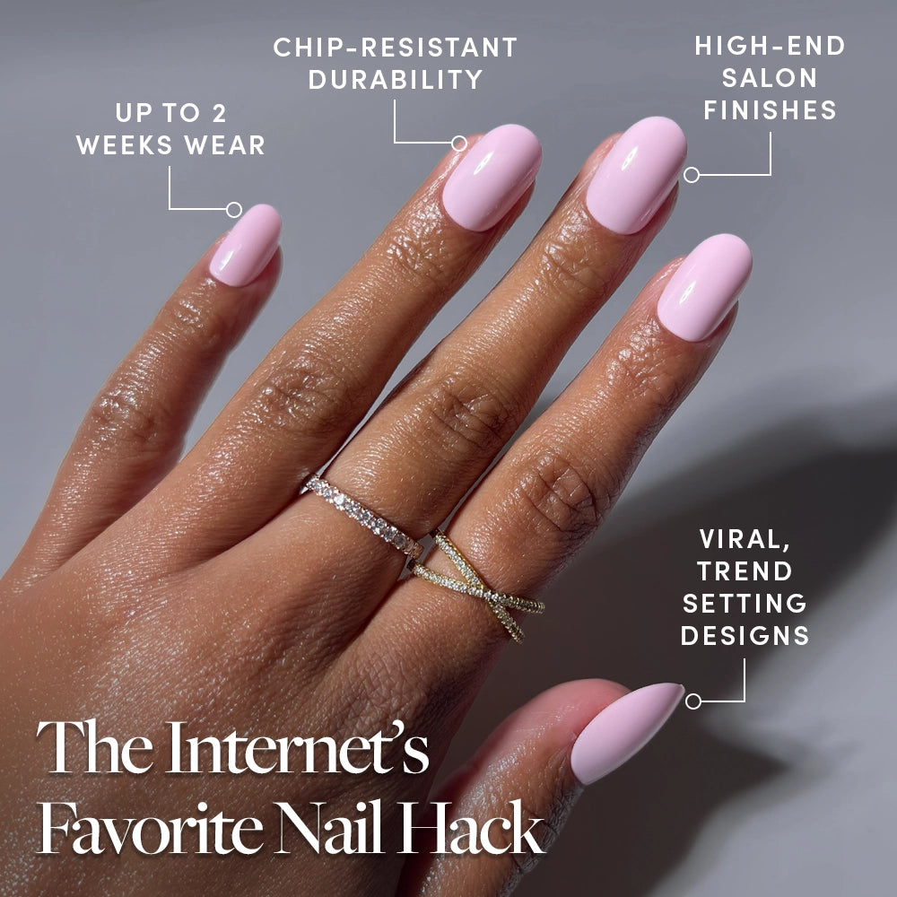 A hand with pink polished nails, wearing two gold rings, models glamnetic’s Pink Permission glossy press-ons—offering up to 2 weeks of chip-resistant wear, salon-quality finishes, and viral trendsetting designs. - Product image