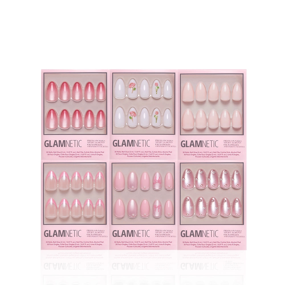 Six sets of short almond Pink Prep School press-on nails from glamnetic—featuring ombre, solid pink, flower patterns, and French tip designs—are displayed in pink glamnetic-branded packaging against a white background. - Product image