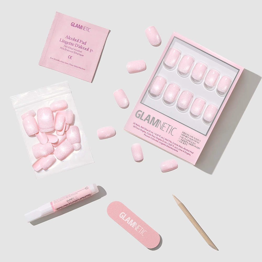 The glamnetic Pinky Promise set features short squoval blush velvet press-on nails, extra vegan cruelty-free nails, an alcohol pad, nail glue, nail file, and cuticle stick—all arranged on a white background. - Product image