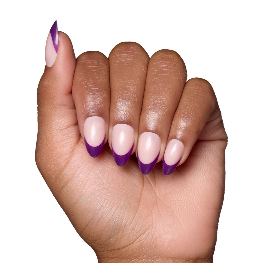 A hand with short almond nails from glamnetics Plum set showcases a nude base with dark purple French tips, all against a white background. - Product image