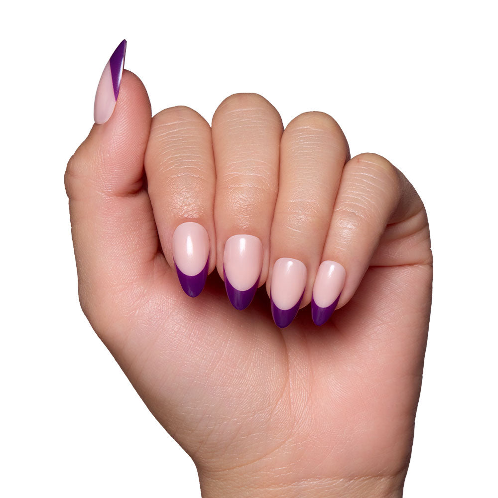 A hand with short almond nails featuring glamnetic’s Plum press-ons: a light pink base with bold, dark purple French tips, against a white background. - Product image