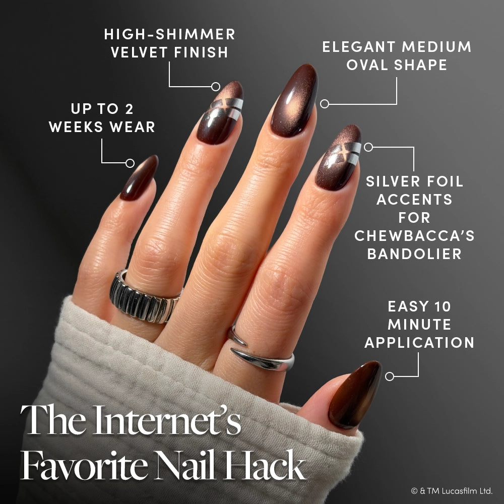 A hand with brown, medium oval nails showcases silver foil details inspired by Chewbacca’s bandolier. The velvet-finish set—Punch It, Chewie by glamnetic—features easy 10-minute application, up to 2 weeks of wear, and includes vegan, cruelty-free press-ons for a truly galactic Star Wars manicure experience. - Product image