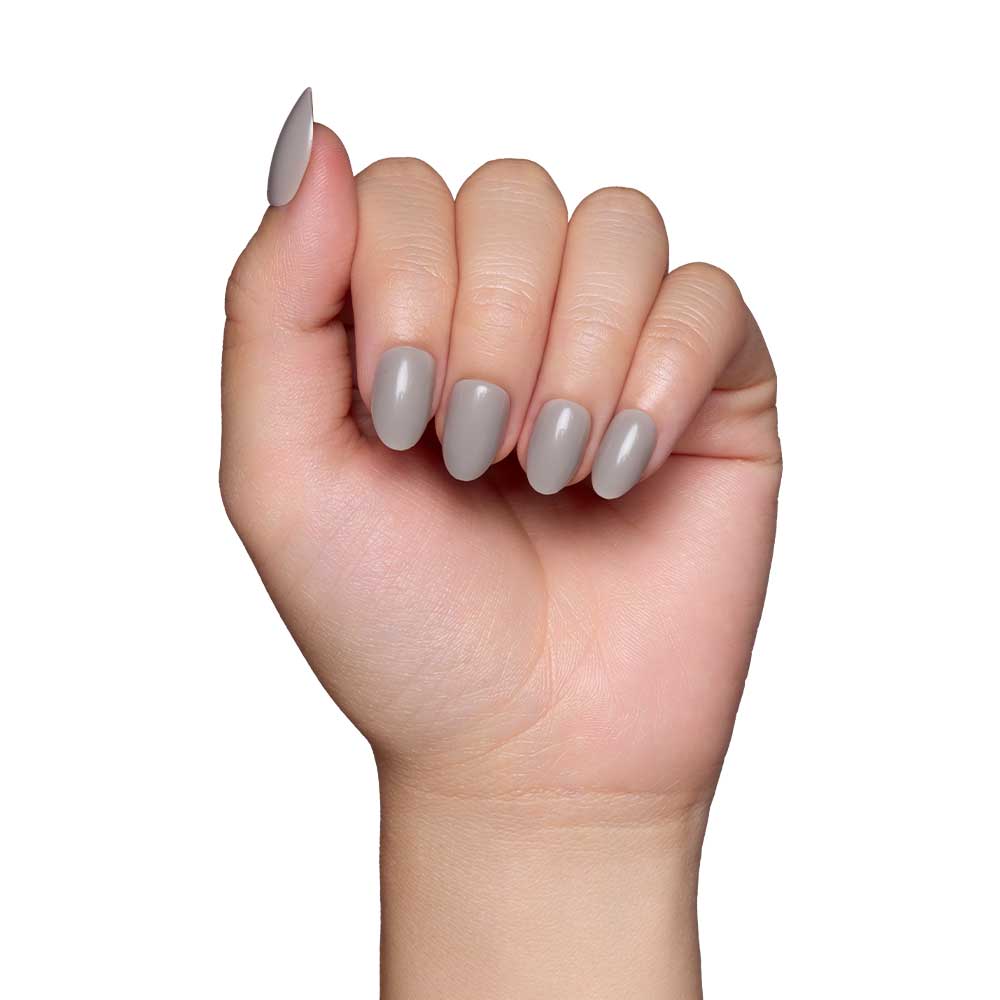 A light-skinned hand with slightly curled fingers displays glamnetics Pure Gray nails, featuring a smooth, glossy light grey finish, set against a plain white background. - Product image