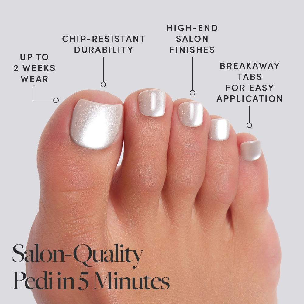 A foot wearing frosted, pearlescent white Glamnetic press-on toenails with product features called out, including salon finish and 2-week wear. - Product image