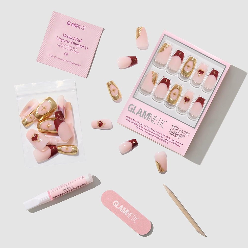 The glamnetic Queen of Hearts press-on nail kit includes pink and burgundy coffin nails, an alcohol pad, nail glue, an emery board, a wood cuticle stick, and a resealable bag—displayed neatly on a white background. - Product image