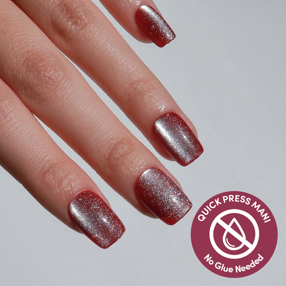 A hand shows off glamnetic's Red Allure: square-shaped, sparkly red press-on nails with a silver gradient. A “QUICK PRESS MANI, No Glue Needed” label highlights the easy, glue-free application.