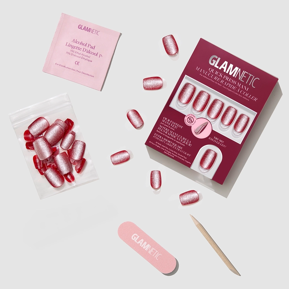 The Glamnetic Red Allure press-on nail kit features red nails and pink glitter accents, plus an alcohol pad, cuticle stick, nail file, nail glue, and extra nails—everything arranged neatly for a quick, glamorous mani. - Product image