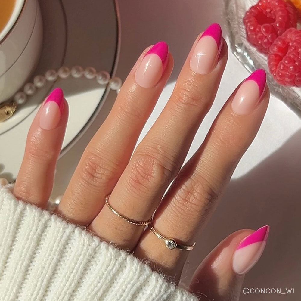 A hand with almond nails sports glamnetics Raspberry Sorbet glossy magenta-pink French tips, paired with two delicate gold rings and a white sweater. Pearls, tea, and raspberries are seen in the background. - Product image