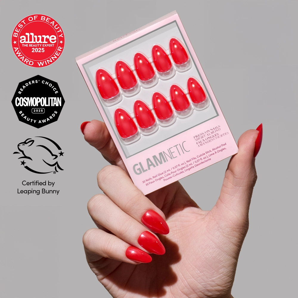 A hand with glazed red nails holds the glamnetic Red Flag short almond press-on nails set. Logos for Allure, Cosmopolitan awards, and Leaping Bunny vegan cruelty-free certification appear on the left of the image.