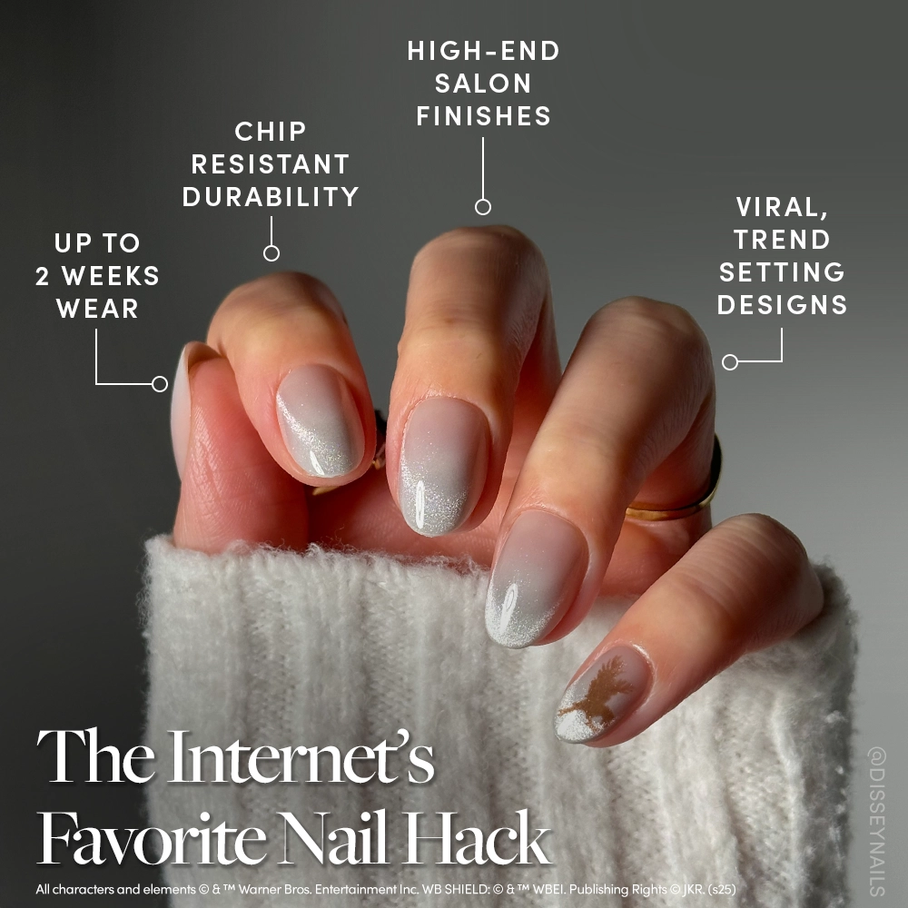 A hand with manicured Rowena Ravenclaw™ by glamnetic velvet oval nails features a glossy light pink ombre and a gold snowflake accent, highlighting durability, trendiness, and salon-quality finish. The person wears a cozy sweater. - Product image