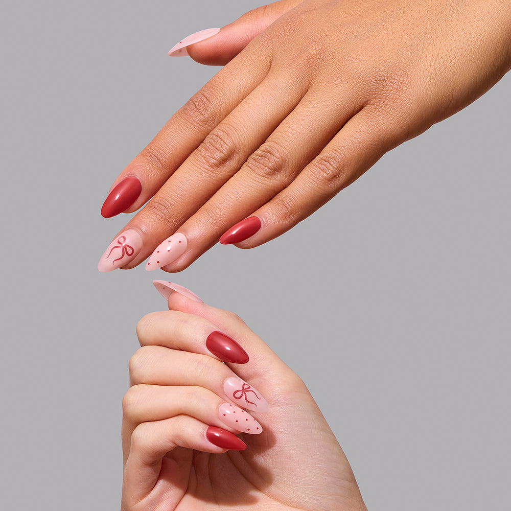 Royal Ribbons - Royal Ribbons almond-shaped press-on nails featuring a mix of solid red polish and light pink nails decorated with red bow and polka dot designs.