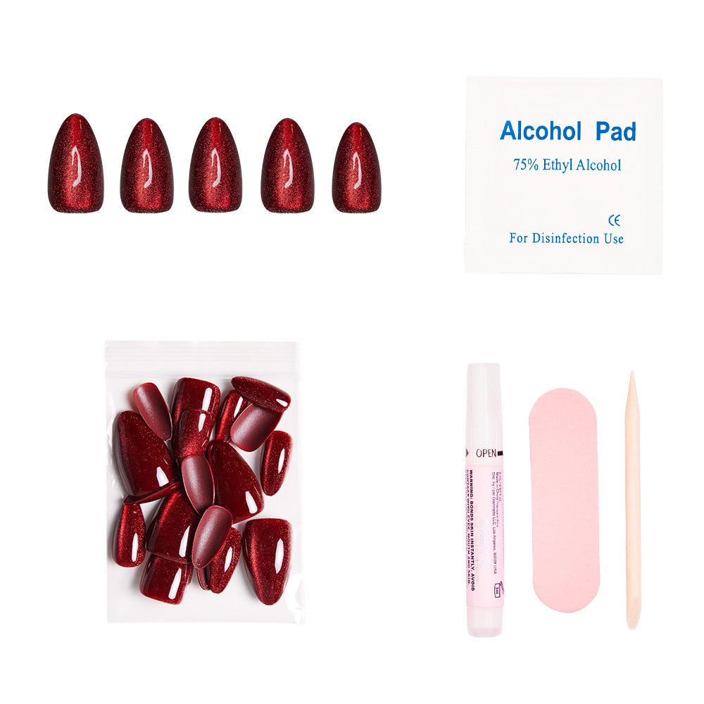 The glamnetic Ruby Slipper set includes short almond red glitter press-on nails, an alcohol pad, extra nails, nail glue, a pink file, and a wooden cuticle stick—all arranged on a white background. - Product image