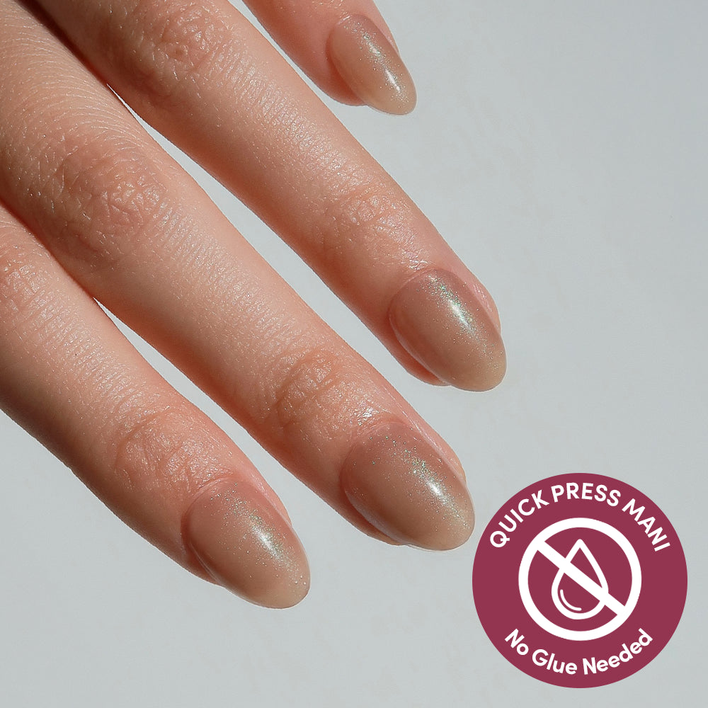 A hand with neatly manicured nails painted in Sparkly Brown, a shimmery nude shade by glamnetic; a badge in the lower right reads Quick Press Mani, no-glue nails for flawless results.