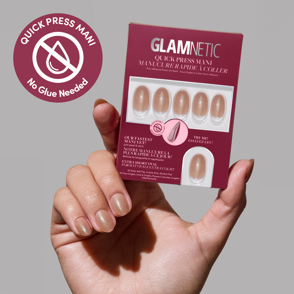 A hand holds a glamnetic Sparkly Brown Quick Press Mani set with five nude stick-on nails. A circular label beside it reads, “QUICK PRESS MANI, No Glue Needed,” with a crossed-out glue icon.