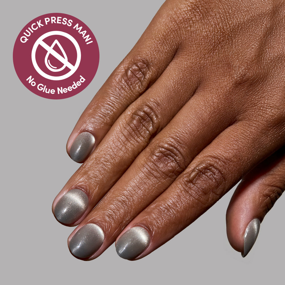 A hand with neatly manicured glamnetic Sparkly Moss press-on nails is shown on a gray background. A badge at the top left reads Quick Press Mani, No Glue Needed, with a crossed-out droplet icon, highlighting these no-glue nails. - Product image